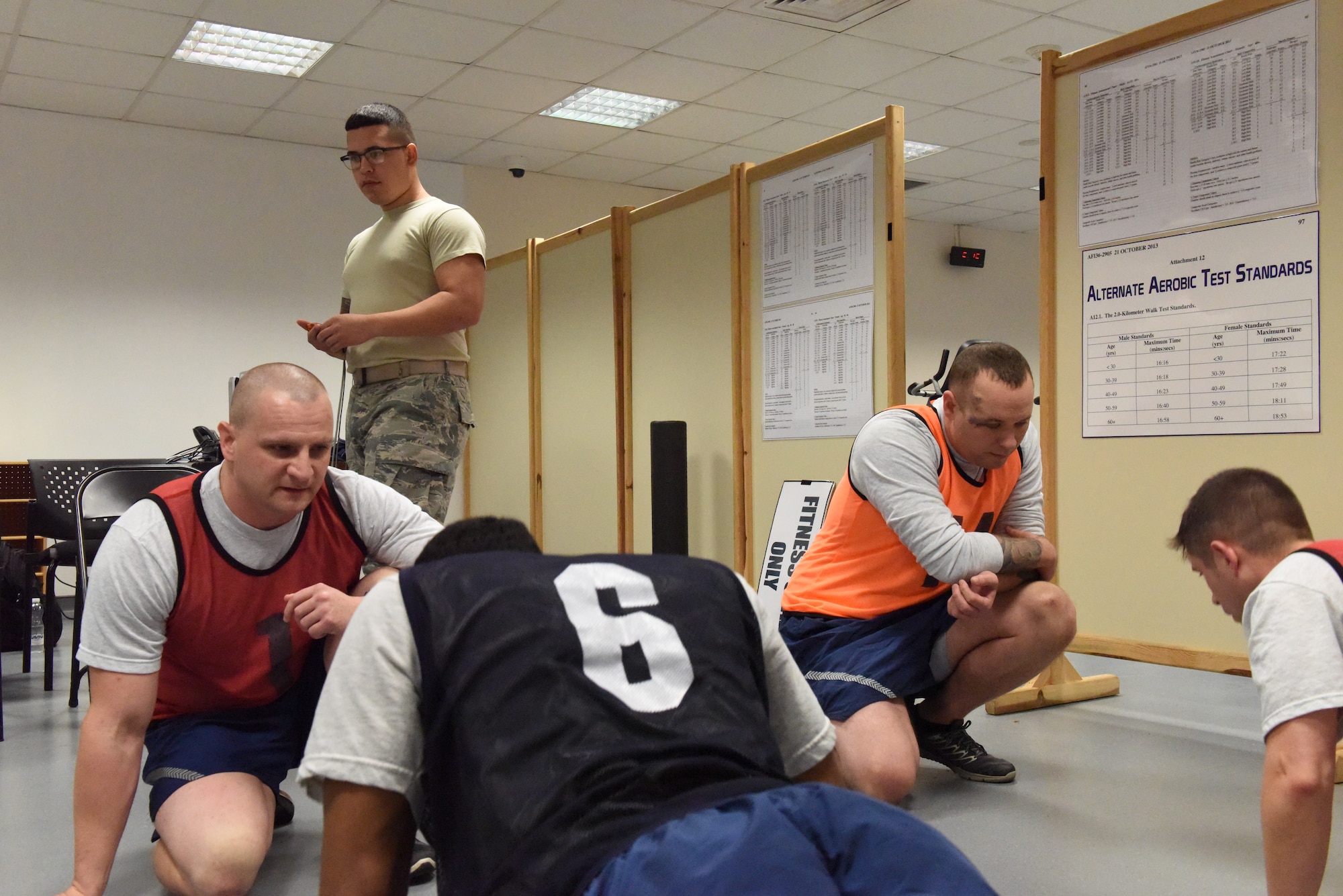 U.S. Air Force Airman 1st Class Jonathan Pena, 39th Force Support Squadron fitness specialist, checks for proper form as service members perform the sit-up portion of their fitness test at Incirlik Air Base, Turkey, Nov. 28, 2018.