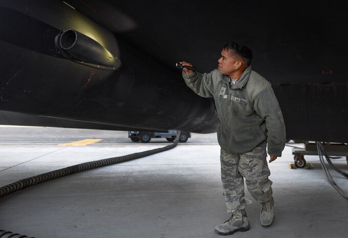An Airman shines a flash light on an aircraft during inspection.