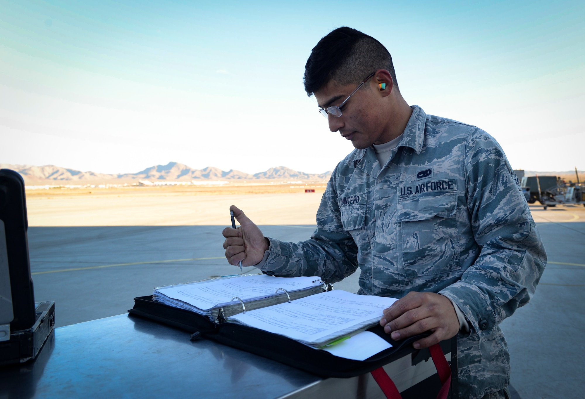 An Airman signs paperwork in a binder on the flight line.