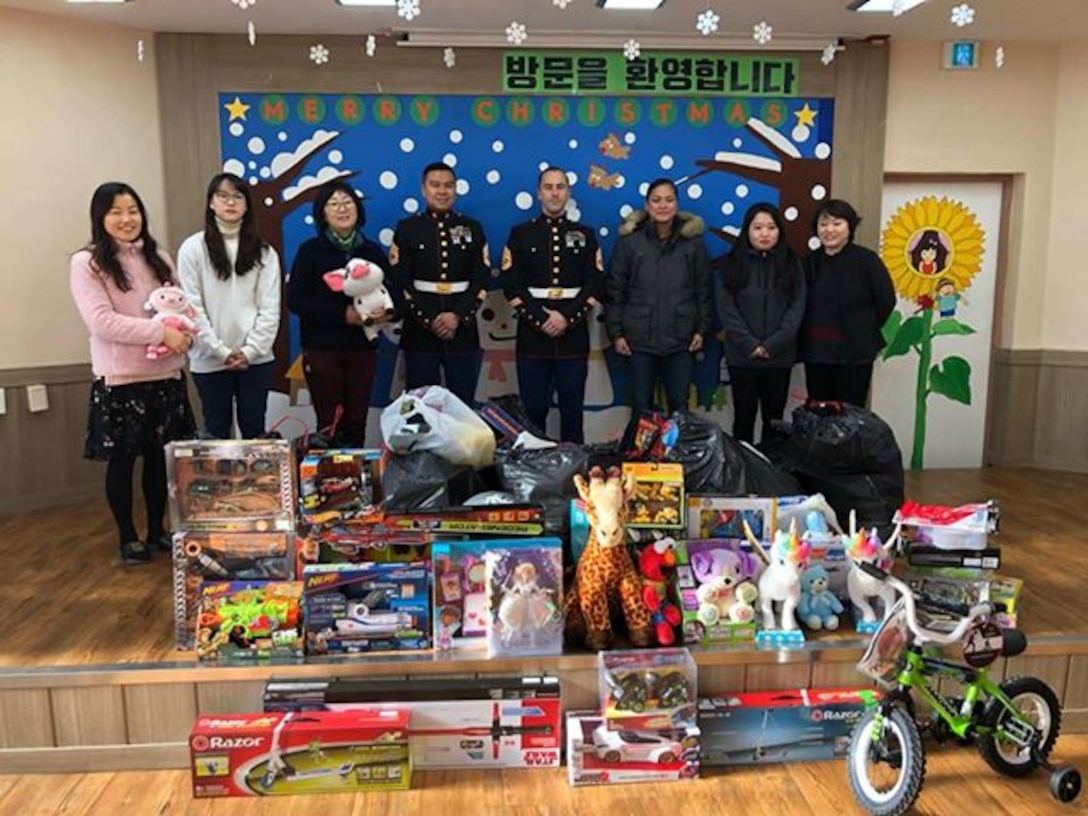 CAMP HUMPHREYS, Republic of Korea - Gunnery Sgt. Hung Tran, G1 Administration Chief, Gunnery Sgt. Christopher Keller, MARFORK Personal Security Detail, and Gunnery Sgt. Tiffany Freeman, G1 Personnel Chief, deliver toys to the Sinasong Orphanage in Pyeongtaek, Republic of Korea, Dec. 22. U.S. Marine Corps Forces Korea collected several thousand toys throughout the 2018 holiday season and delivered them to thirteen orphanages in Seoul and Pyeongtaek. (Courtesy photo by GySgt. Hung Tran)