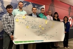Team members from DLA Troop Support Subsistence and Continuous Process Improvement Offices hold the process map created for the UGR-A process improvement project Sept. 19, 2018 in Philadelphia, Pennsylvania.