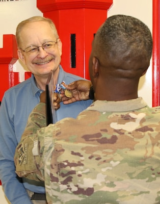 Col. Jason E. Kelly, Afghanistan District Commanding Officer pins the Global War on Terrorism Medal and NATO medal on Mark A. Coburn for his outstanding work ethics while deployed in support of Operation Freedom’s Sentinel.
