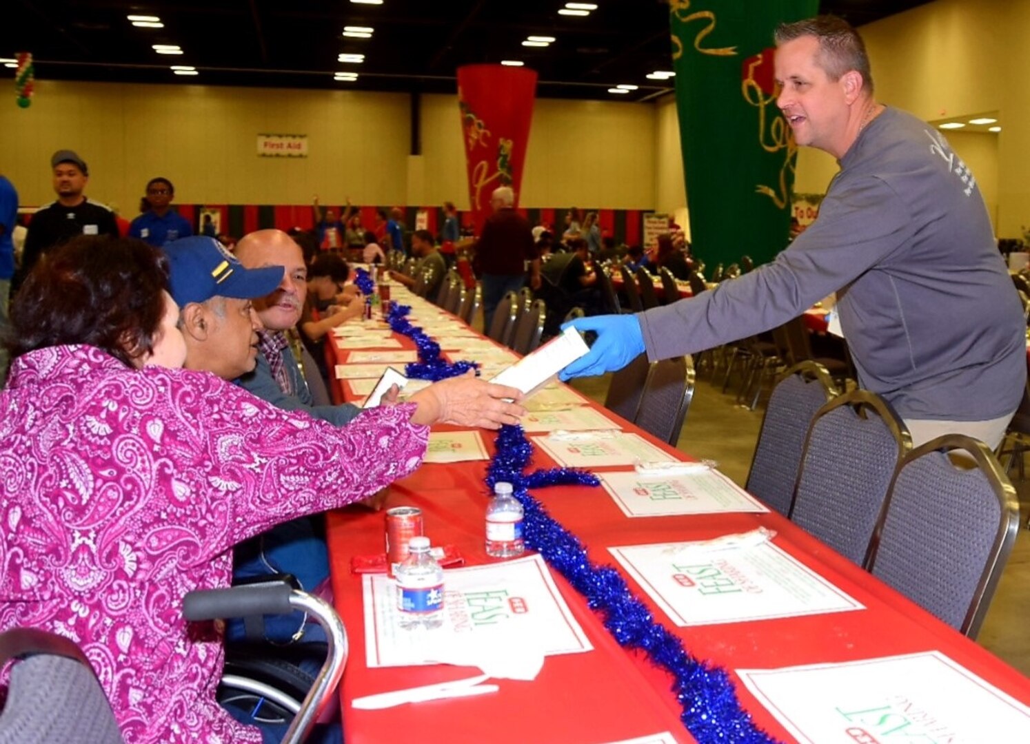 Lt. Col. Marc Mulkey, 733rd Training Squadron commander, passes out boxes of cookies to one of the 10,000 guests at 
H-E-B’s 26th Annual Feast of Sharing Dec. 23, 2018, at the Henry B. Gonzalez Convention Center in San Antonio. Mulkey brought his wife and children to help serve at the event and he said that he hopes to bring his family to serve again next year.