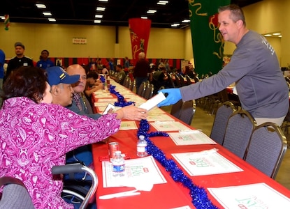 Lt. Col. Marc Mulkey, 733rd Training Squadron commander, passes out boxes of cookies to one of the 10,000 guests at 
H-E-B’s 26th Annual Feast of Sharing Dec. 23, 2018, at the Henry B. Gonzalez Convention Center in San Antonio. Mulkey brought his wife and children to help serve at the event and he said that he hopes to bring his family to serve again next year.