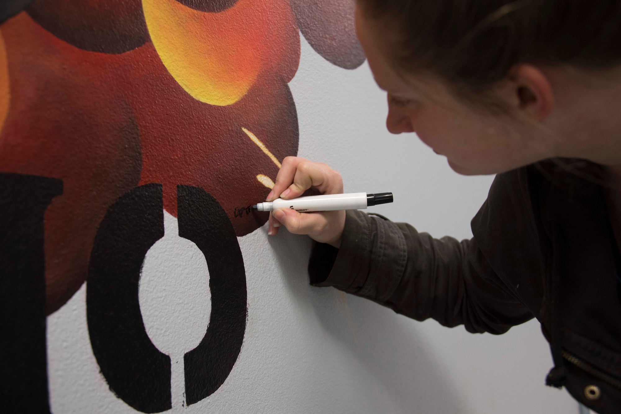 U.S. Air Force Staff Sgt. Ashley Johnson, 707th Maintenance Squadron munitions technician, signs a mural she created for the 307th MXS at Barksdale Air Force Base, Louisiana, Jan. 4, 2019.  (U.S. Air Force photo by Master Sgt. Ted Daigle)