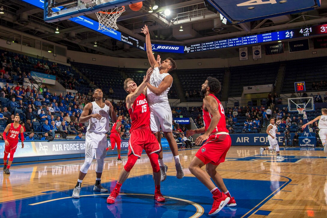 Air Force cadet takes a jump shot in a basketball game while being guarded by an opposing team.