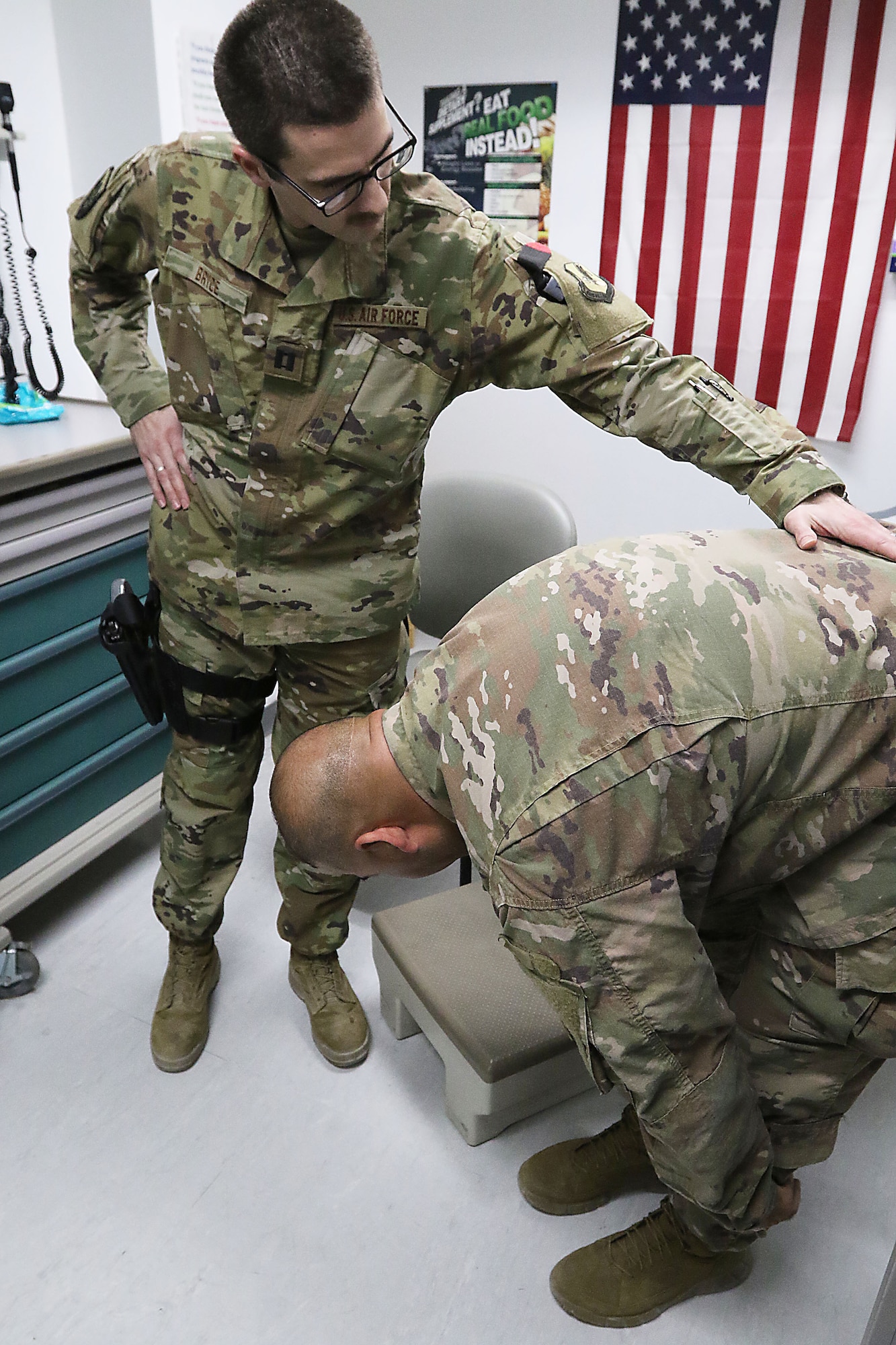 Chief Warrant Office 2 George Scott shows his improved range of motion of his lower back to Air Force Dr. (Capt.) Carl Bryce during a status evaluation Dec. 2 at the Craig Joint Theater Hospital at Bagram Airfield, Afghanistan.