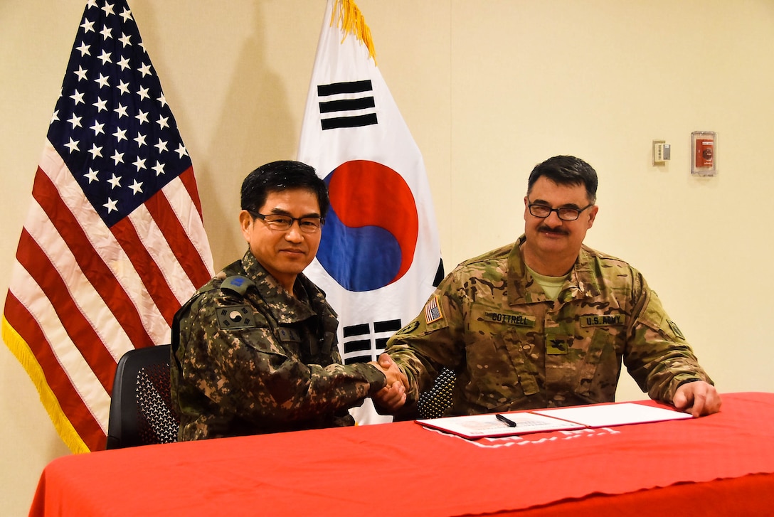 Col. Park Jong Yeon (left), Republic of Korea DCA, MND-DIA and Col. Garrett Cottrell, USACE FED deputy commanding officer- Transformation/USDCA, sign the Acceptance Release Memorandums for the SLQ031 Unaccompanied Officers Personnel Housing and UEH050 Enlisted Barracks, Camp Humphreys, South Korea, Dec 18.