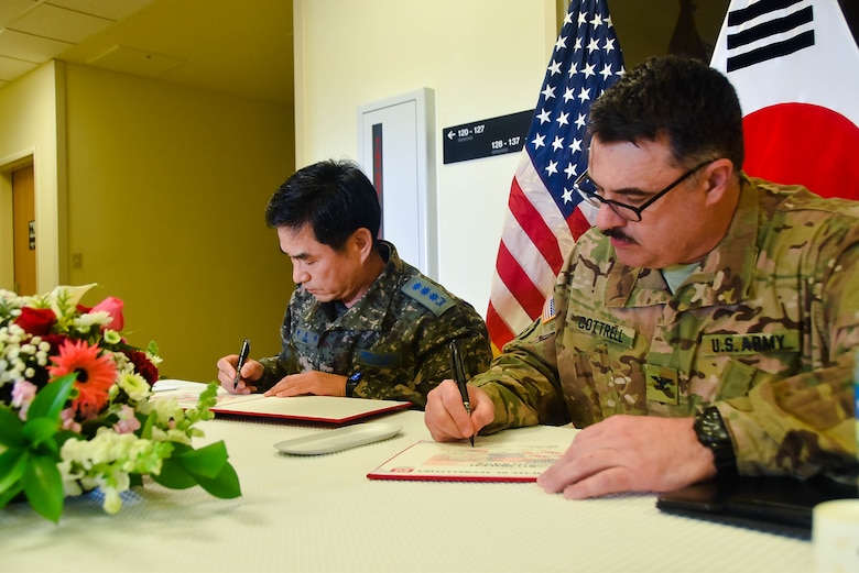 Col. Park Jong Yeon (left), Republic of Korea DCA, MND-DIA and Col. Garrett Cottrell, USACE FED deputy commanding officer- Transformation/USDCA, sign the Acceptance Release Memorandums for the SLQ031 Unaccompanied Officers Personnel Housing and UEH050 Enlisted Barracks, Camp Humphreys, South Korea, Dec 18.