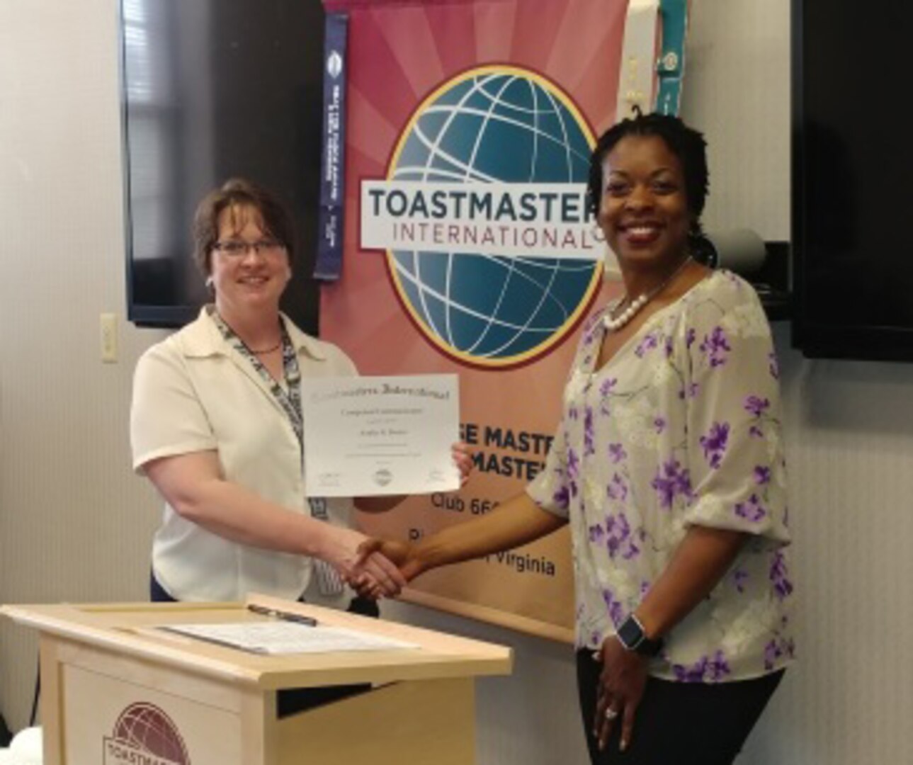 Toastmaster Area 34 Director LaShawanda Moore present Amber Brister with Competent Communicator certificate