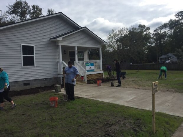 Space and Naval Warfare Systems Center (SSC) Atlantic New Professionals (NPs) dig rocks out of the front yard of a Habitat for Humanity home.
