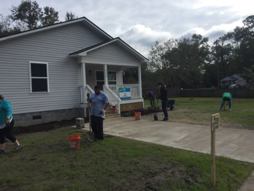 Space and Naval Warfare Systems Center (SSC) Atlantic New Professionals (NPs) dig rocks out of the front yard of a Habitat for Humanity home.