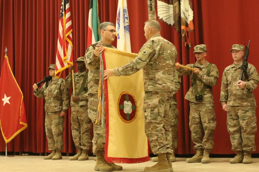 Brig. Gen. Clint E. Walker, and Command Sgt. Maj. Jason Little, 184th Sustainment Command, uncase the unit colors during the 143d and 184th Sustainment Commands transfer of authority ceremony at Camp Arifjan, Kuwait, Jan. 2, 2019.