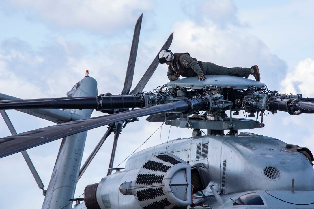 A Marine lies on top of a helicopter.