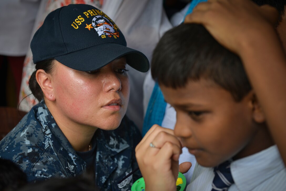 A service member paints a student's face.