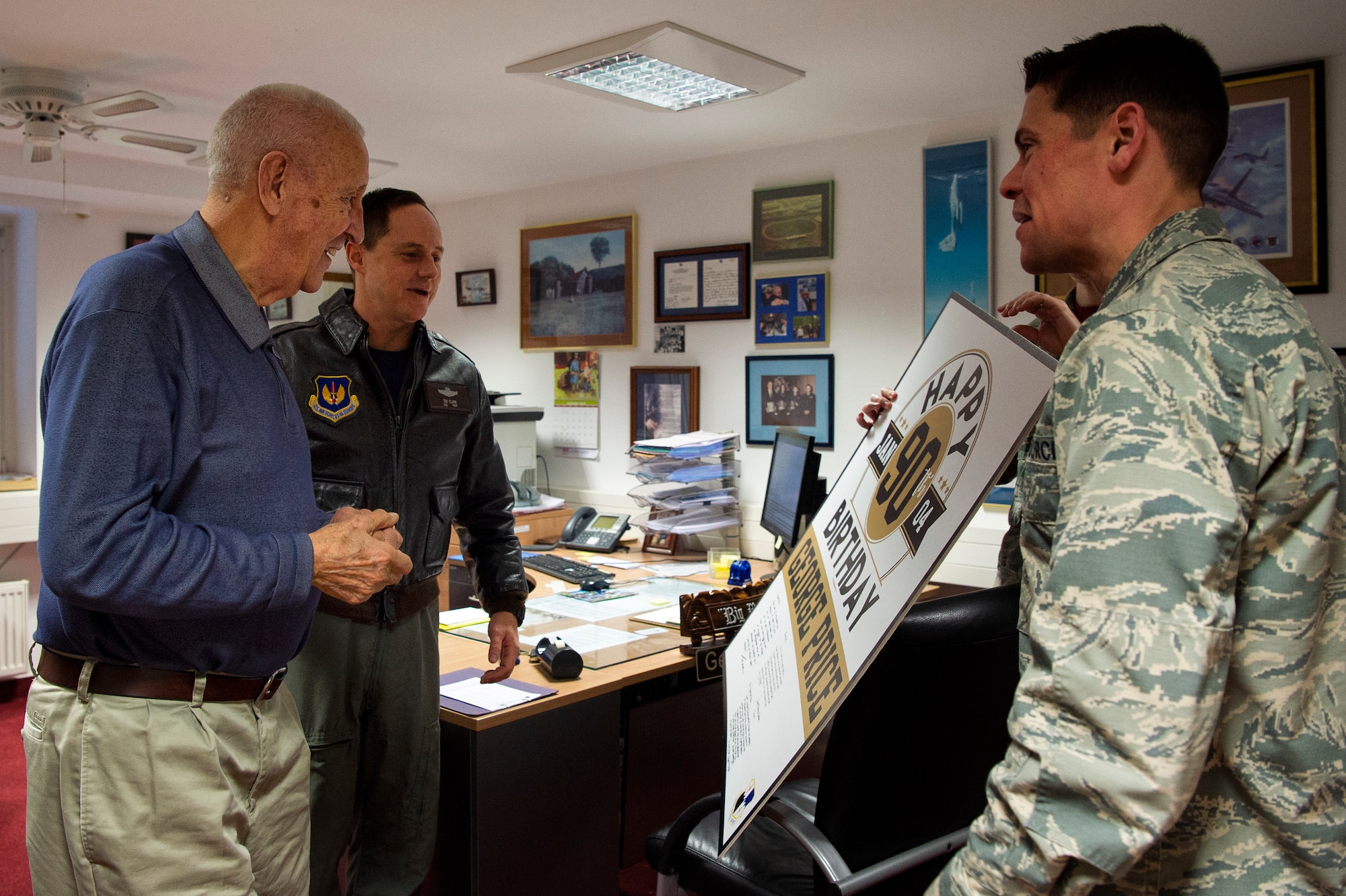 George Price, 52nd Force Support Squadron special events coordinator, left, celebrates his 90th birthday at Spangdahlem Air Base, Germany, Jan. 4, 2019. U.S. Air Force Col. Tad Clark, 52nd Fighter Wing vice commander, center left, and Maj. Steven Massara, 52nd Wing Staff Agency executive officer, right, presented Price with a card. Price was a basketball coach on Bitburg Air Base and became the winningest head coach in U.S. Air Forces in Europe history. He has held his current position since 2002. (U.S. Air Force photo by Airman 1st Class Valerie Seelye)