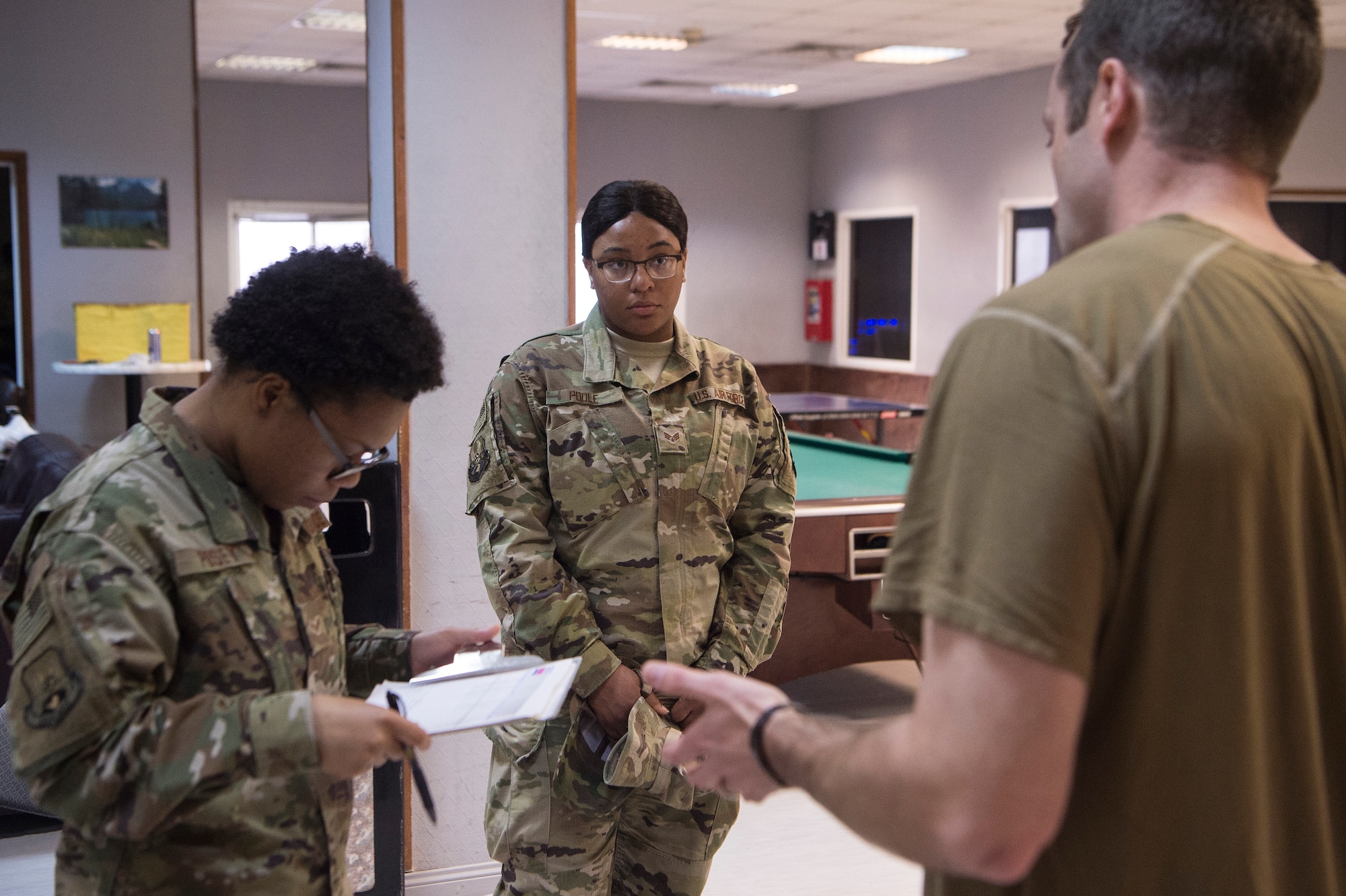 Airman 1st Class Dakaysiah Posey, left, and Senior Airman Daja Poole, center, both 379th Expeditionary Logistics Readiness Squadron (ELRS) Air Force Transient Reception Control Center logistics planners, answer an Airman’s question at Al Udeid Air Base, Qatar, Jan. 5, 2019. 379th ELRS log planners relay transportation information to service members traveling to deployed locations across U.S. Central Command’s area of responsibility. They provide warfighters in transition support including lodging, means of communication and vehicles to ensure mission effectiveness as they wait for forward deployment.  (U.S. Air Force photo by Tech. Sgt. Christopher Hubenthal)