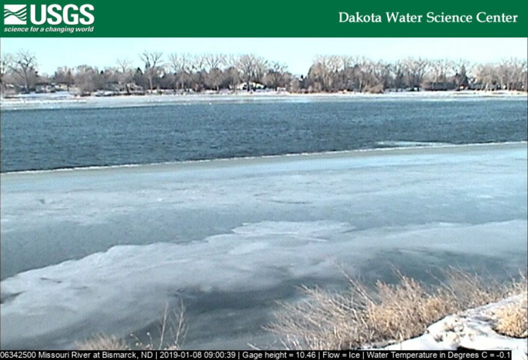 The Missouri River, while not frozen over completely, has ice forming on the shore.