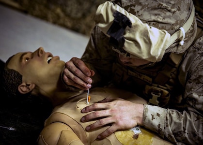 Seaman Brandon Taylor, a corpsman, inserts a decompression needle into an essential care simulator manikin during shock trauma section drills. The drills focused on sharpening life-saving skills and capabilities.