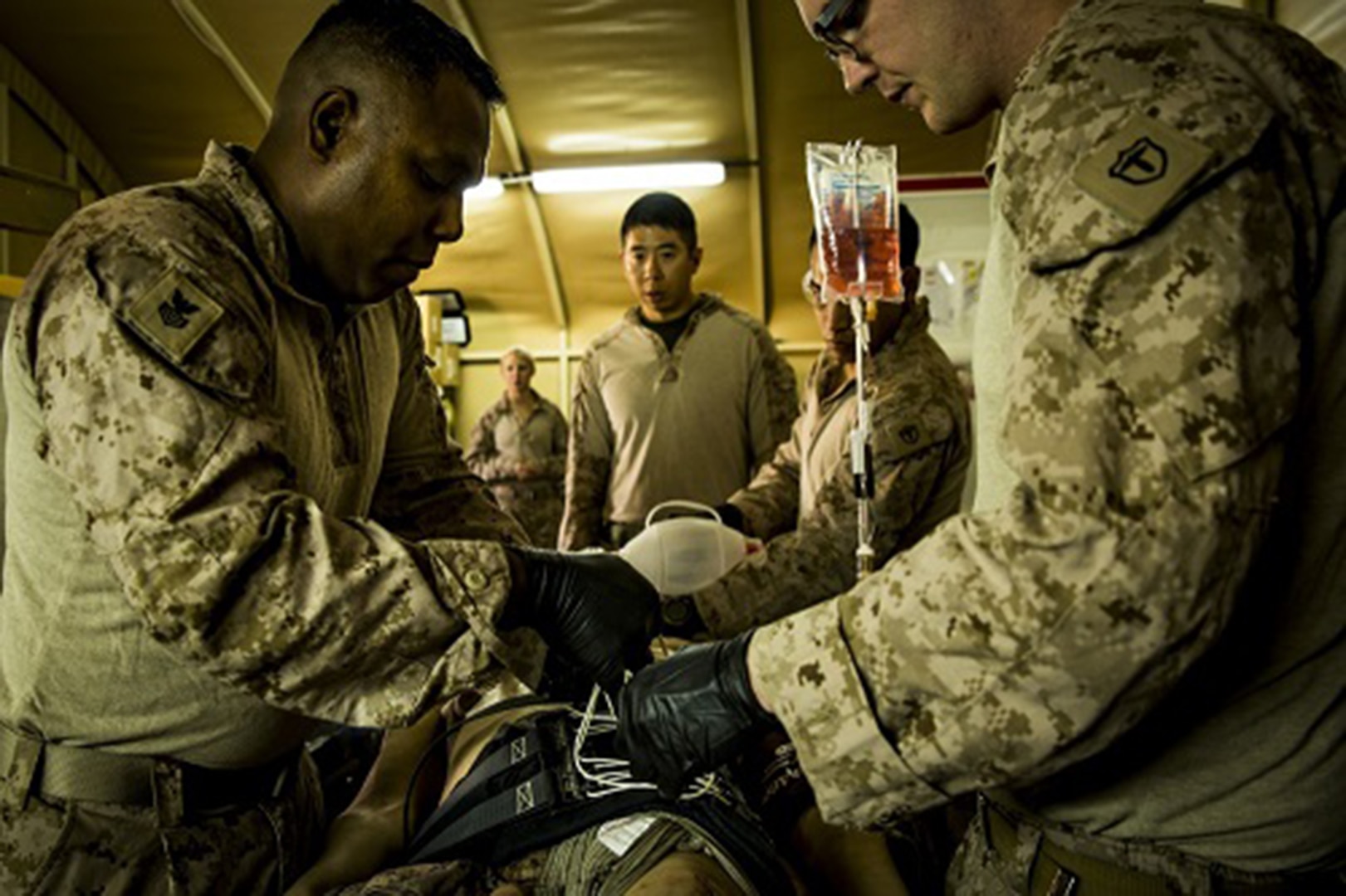 Navy Petty Officer 1st Class Cesar Borrero (left), an X-ray technician, and Seaman Andrew Ott, a field medical technician, fasten a pelvic stabilization device to an essential care simulator manikin during shock trauma section drills.