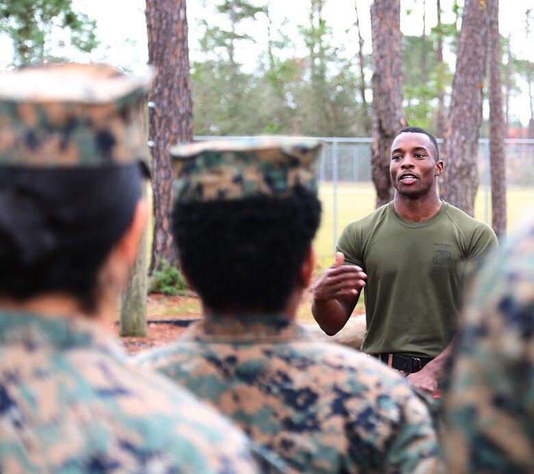 Sgt. Darius L. Warren, left, supply administration and operations specialist, G6, Marine Corps Logistics Command, addresses Marines during his reenlistment at the obstacle course aboard Marine Corps Logistics Base Albany, Ga., Dec. 19. Warren and Maj. Danny A. Hamler, logistics analyst, G3/5, LOGCOM, and officiating officer, climbed to the top of the rope and recited the oath of enlistment.