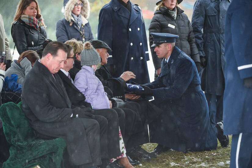 DIA Command Senior Enlisted Leader Chief Master Sgt. Benjamin Higginbotham presents the burial flag to Frank Henrion, husband of the late Chief Master Sgt. Therese Henrion, during her graveside burial at Arlington National Cemetery, Nov. 15, 2018.