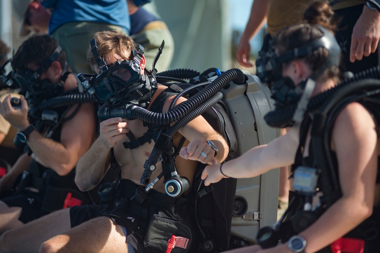 Sailors in diving gear prepare to enter training pool.