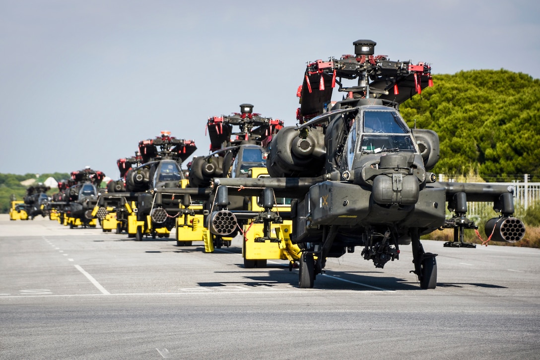 Helicopters move in a line on an asphalt strip.