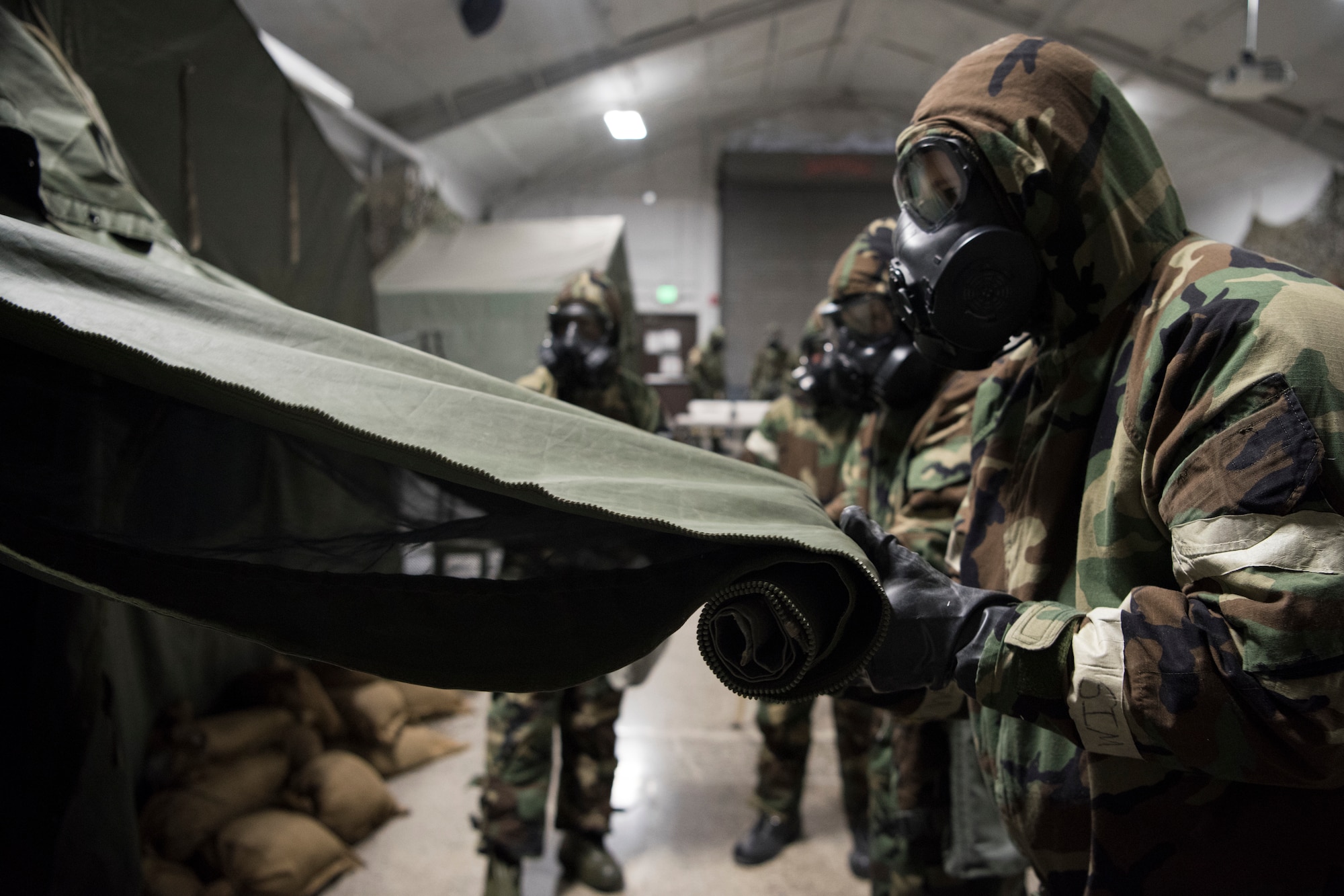 A group of U.S. Air Force Airmen roll up a tent door during a newly-implemented chemical, biological, radiological and nuclear defense training course exercise at Joint Base Elmendorf-Richardson, Alaska, Jan. 8, 2019. One of the key changes made embraces the reintegration of hands-on, in-person instruction, and reduces computer based training, allowing Airmen to receive a more tailored learning experience. (U.S. Air Force photo by Airman 1st Class Crystal A. Jenkins)