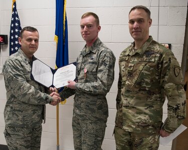 U.S. Brigadier General Darrin Slaten, commander of the 176th Wing, Alaska Air National Guard, joined by U.S. Army Sgt. 1st Class Shawn Landon, presents U.S. Air Force Airman 1st Class Daniel Randolph The Alaska Humanitarian Service Medal during a ceremony at Joint Base Elmendorf-Richardson, Alaska Jan. 9, 2019. Randolph was awarded the medal for exceptional response after witnessing a para-gliding accident on March 10, 2018 while hiking. Randolph assumed personal risk to reach the pilot by climbing an ice laden cliff and provided immediate aid by fashioning a sling, he was also able to grab the pilot’s gear, guide the pilot down the cliff as well as the Butte Trail.