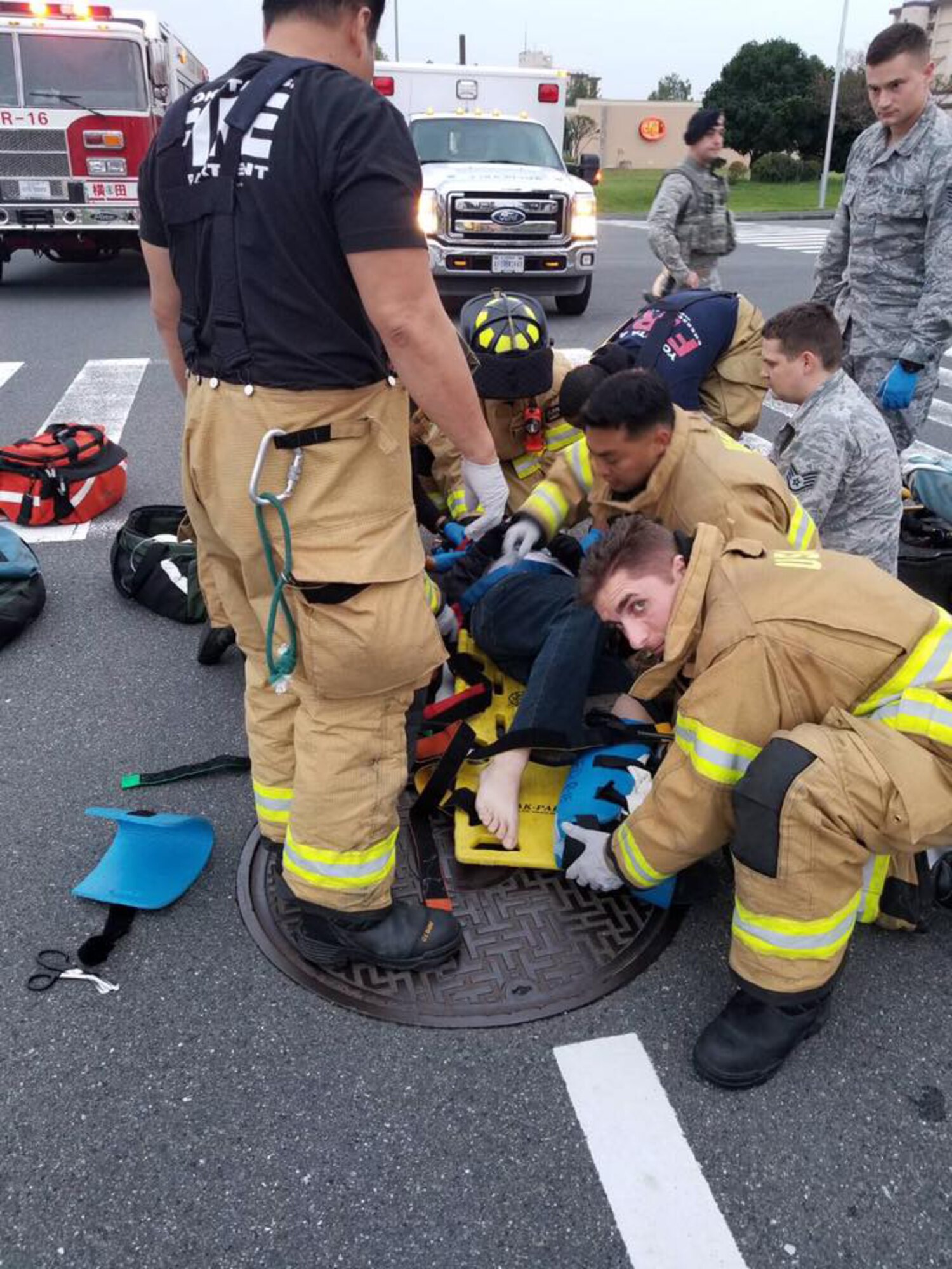 374th Airlift Wing emergency personnel load Staff Sgt. Kyle Johnson, a photojournalist with the 374th Airlift Wing Public Affairs office, onto a stretcher for transport to the hospital, October 4, 2018. Johnson received immediate surgery and later a second surgery for a compound fracture to his tibia and fibula. (U.S. Air Force photo by John Souza)