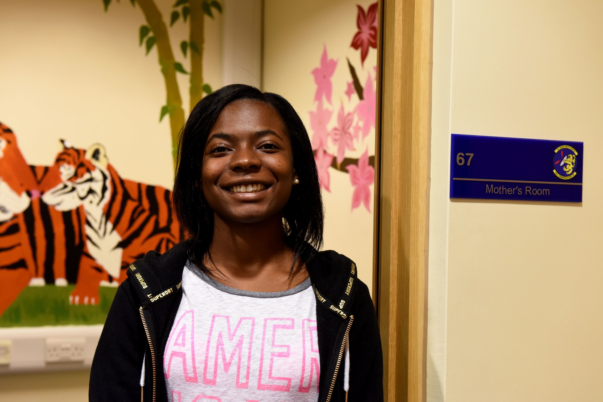 Volunteer Nadja Ellis poses for a picture at the Mothers’ Room in the 100th Communications Squadron building at RAF Mildenhall, England, Jan. 7, 2019.  Ellis painted a children’s picture book-themed mural to create a tranquil space for new mothers to breastfeed.   (U.S. Air Force photo by Senior Airman Lexie West)