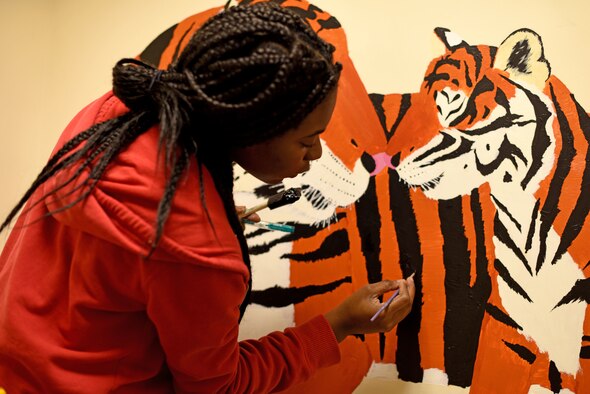 Volunteer Nadja Ellis paints tiger stripes for a mural in the 100th Communications Squadron building at RAF Mildenhall, England, Dec. 20, 2018. Ellis painted the mural to cover the walls of the Mothers’ Room and create a tranquil space for new mothers to breastfeed.  (U.S. Air Force photo by Senior Airman Lexie West)