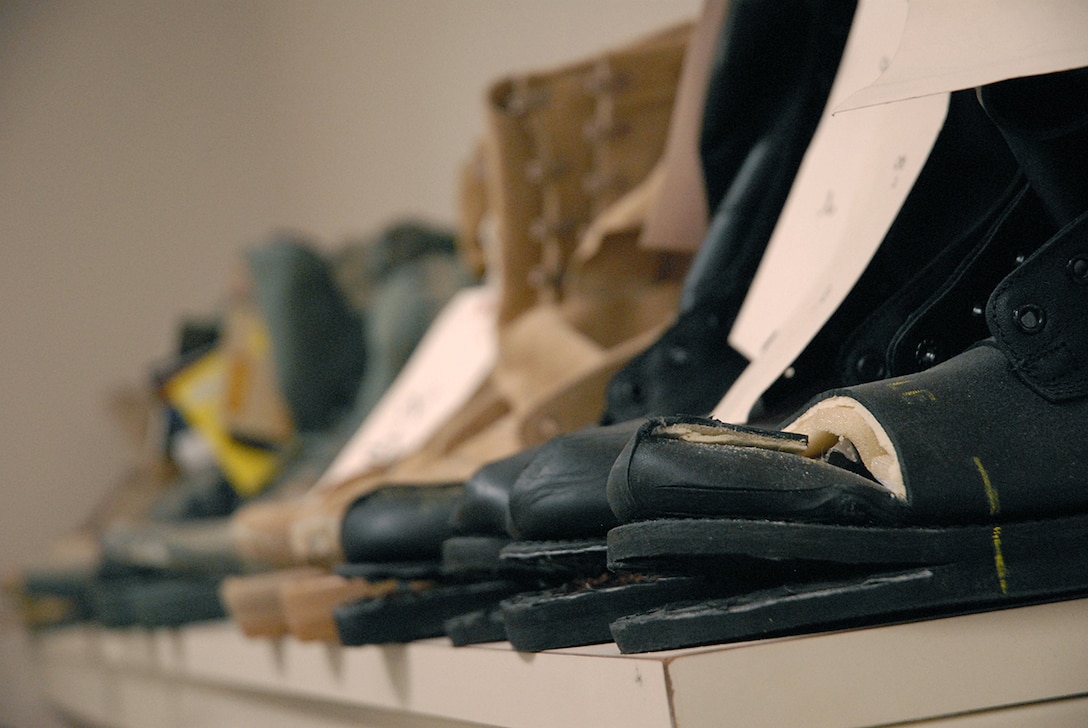 Military-issue boots that have been ripped, cut and sole-split line the wall in one of the Product Test Center-Analytical labs. Boots are tested a variety of ways to ensure service members are protected from the elements and hazards they work with and to ensure comfort.