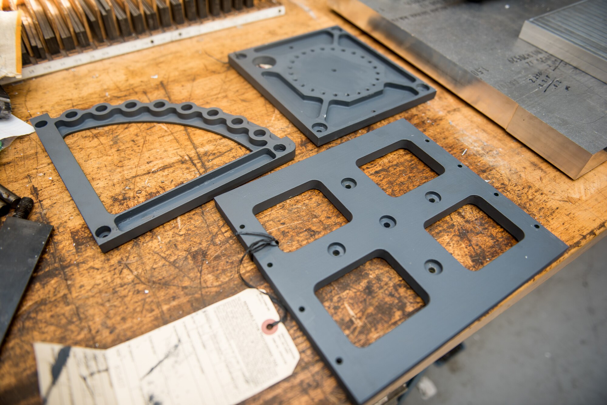 Three HH-60G Pave Hawk helicopter plates are set on a fabrication workshop table at Dover Air Force Base, Delaware, Jan. 6, 2019. The 920th Rescue Wing at Patrick AFB provided these three plates as samples for the 512th Maintenance Squadron to replicate. (U.S. Air Force photo by Staff Sgt. Damien Taylor)