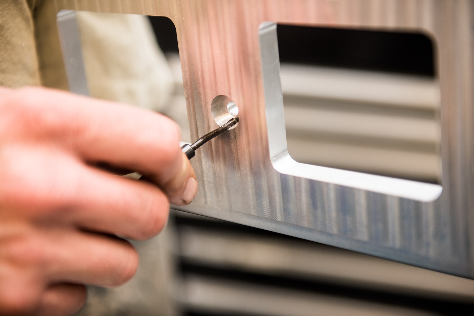 Staff Sgt. Tyler Dickson, 512th Maintenance Squadron aircraft metal technician, deburrs the edges of cradle plate at Dover Air Force Base, Delaware, Jan. 6, 2019. A deburring tool is utilized to dull sharp edges. (U.S. Air Force photo by Staff Sgt. Damien Taylor)