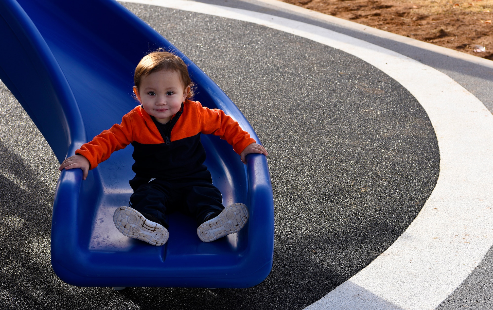 A young Thunderbolt smiles after riding down a slide at the new Fowler Park playground, Jan. 9, 2019, at Luke Air Force Base, Ariz.