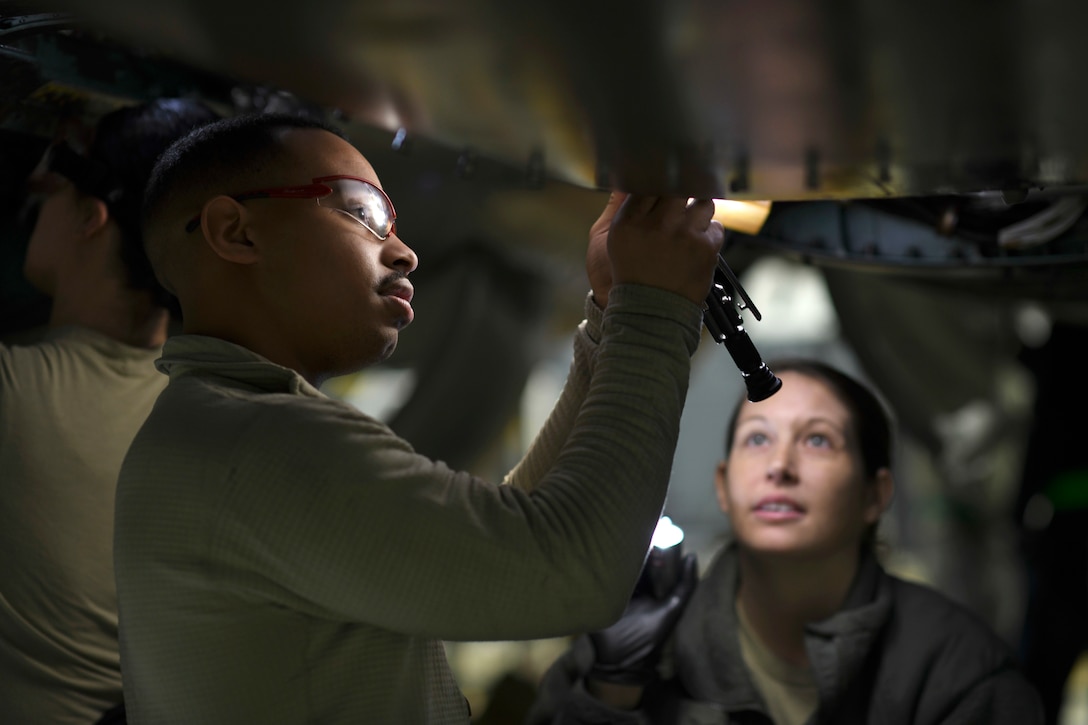 Air Force maintainers work under an aircraft.