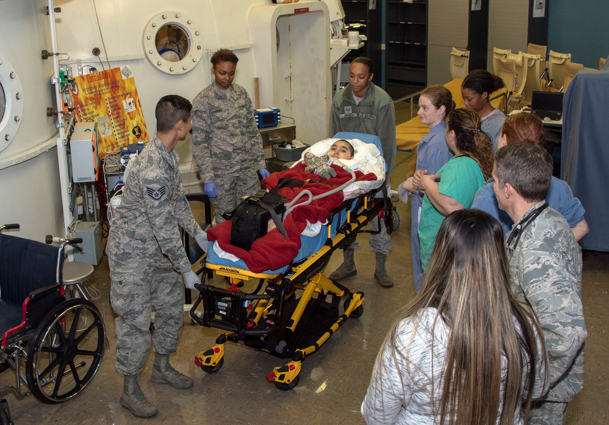 Hyperbaric Medicine Flight personnel and Aerospace Expeditionary Force personnel transport cancer patient Jeremiah Harutyunyan by gurney after he received hyperbaric oxygen treatment, Dec. 8, 2019, at David Grant USAF Medical Center, Travis Air Force Base, California. (U.S. Air Force Photo by Heide Couch)