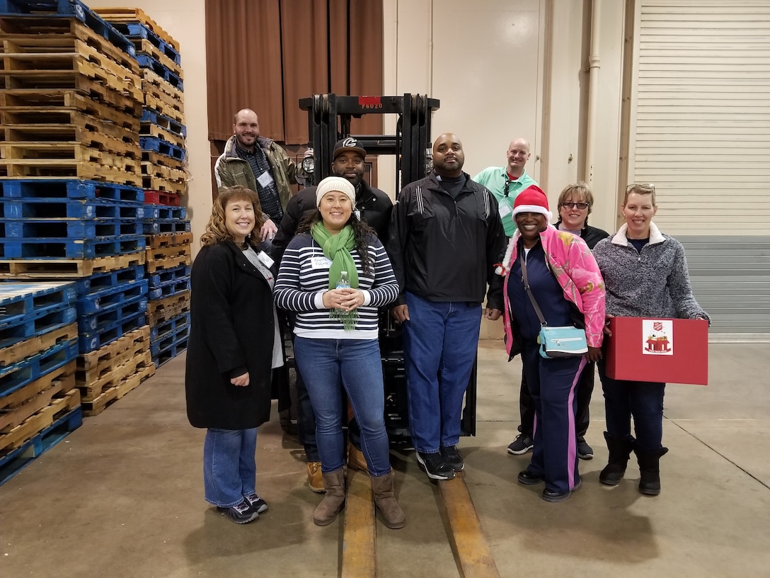 Volunteers stand around a forklift in a warehouse for a photo