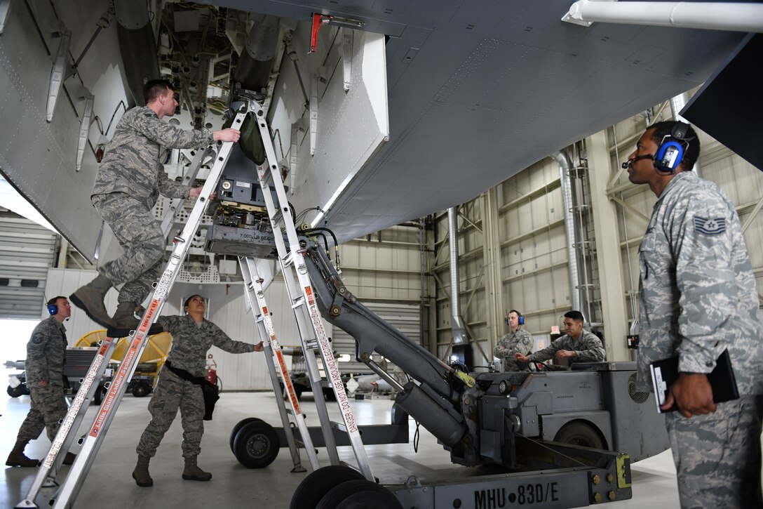 Judges for the annual weapons load competition watch as the 28th Munitions Squadron load crew install a second GBU-38 Joint Direct Attack Munition onto a simulated B-1 bomber at Ellsworth Air Force Base, S.D., Jan. 7, 2019. Participants competed to be recognized as the 28th Maintenance Group’s best load crew for 2018. (U.S. Air Force photo by Airman 1st Class Christina Bennett)