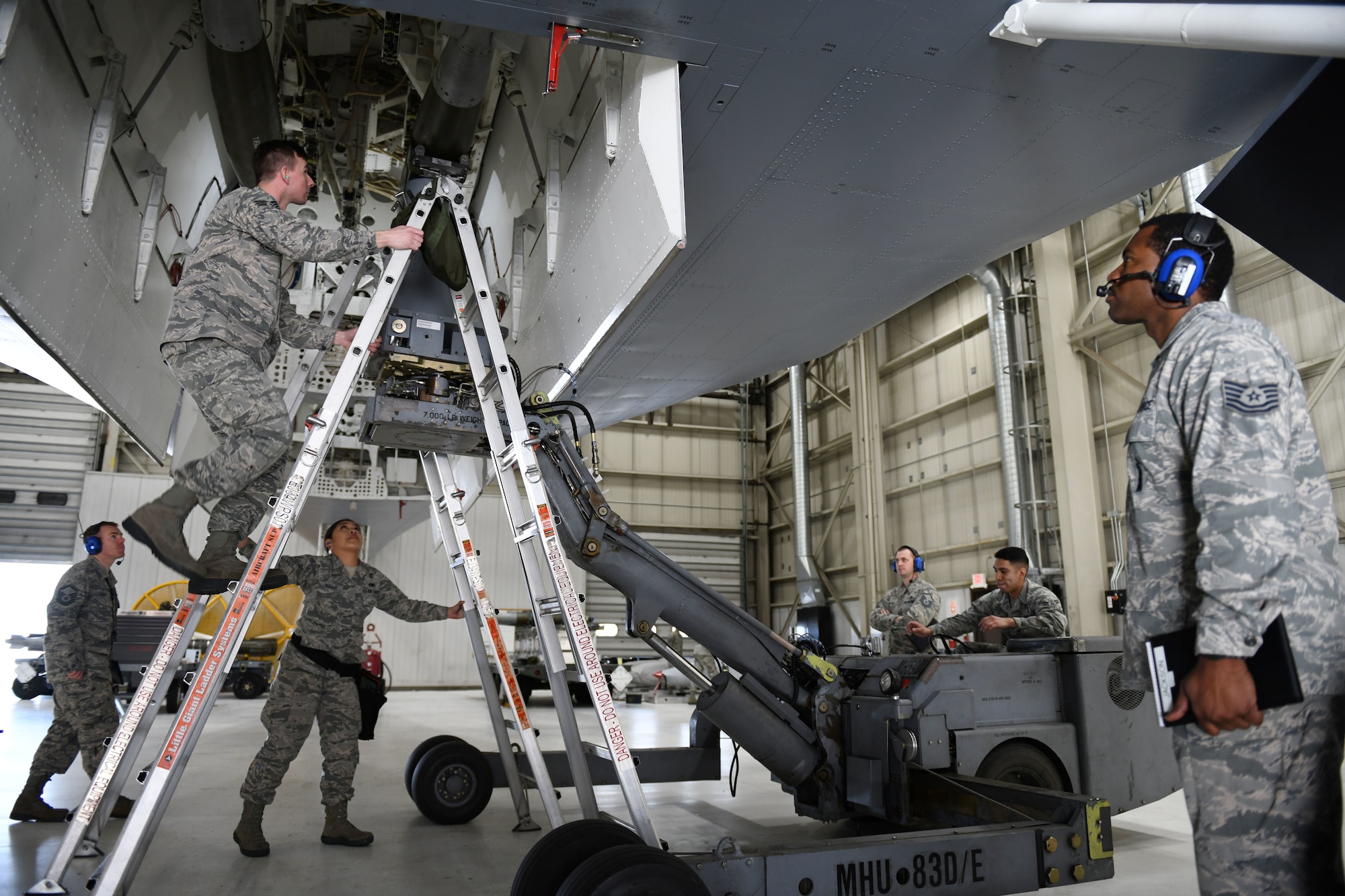 Judges for the annual weapons load competition watch as the 28th Munitions Squadron load crew install a second GBU-38 Joint Direct Attack Munition onto a simulated B-1 bomber at Ellsworth Air Force Base, S.D., Jan. 7, 2019. Participants competed to be recognized as the 28th Maintenance Group’s best load crew for 2018. (U.S. Air Force photo by Airman 1st Class Christina Bennett)