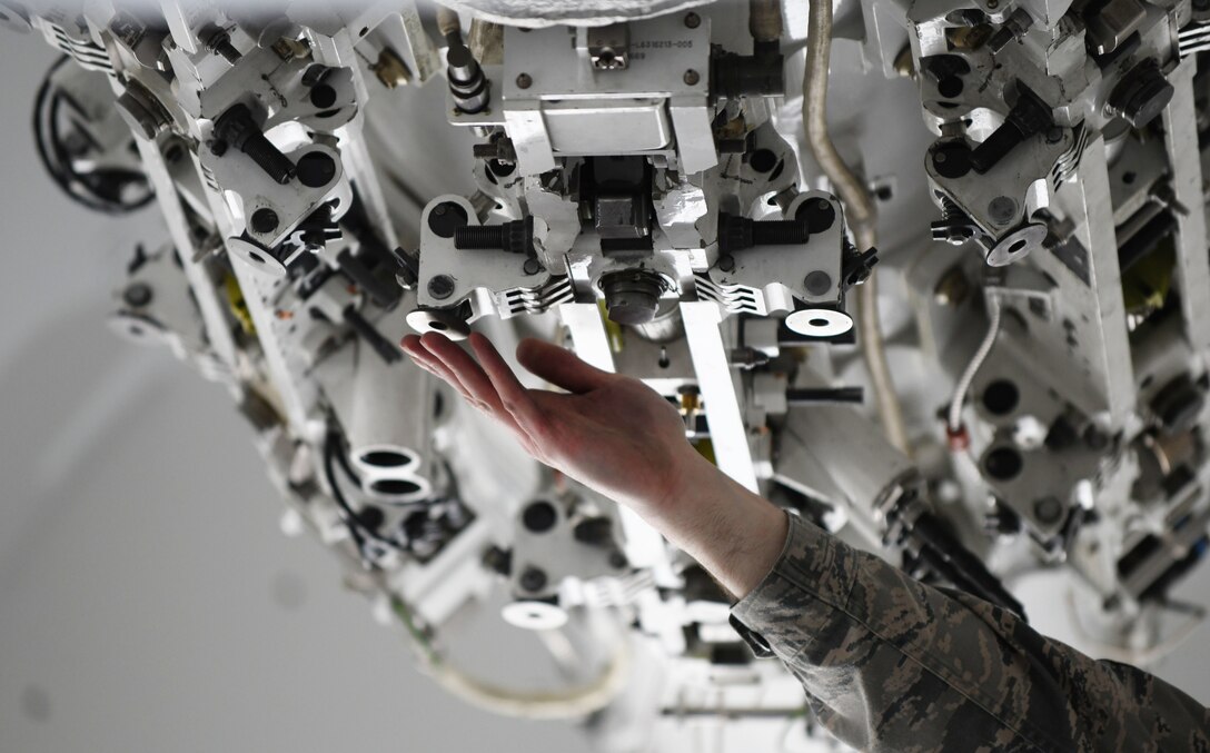 A load crew member participating in the annual weapons load competition inspects a bomb rack prior to loading a munition onto a simulated B-1 bomber at Ellsworth Air Force Base, S.D., Jan. 7, 2019. A small cartridge is installed onto the rack that will release the bomb from the aircraft, so the rack must be inspected as well as the munition. (U.S. Air Force photo by Airman 1st Class Christina Bennett)
