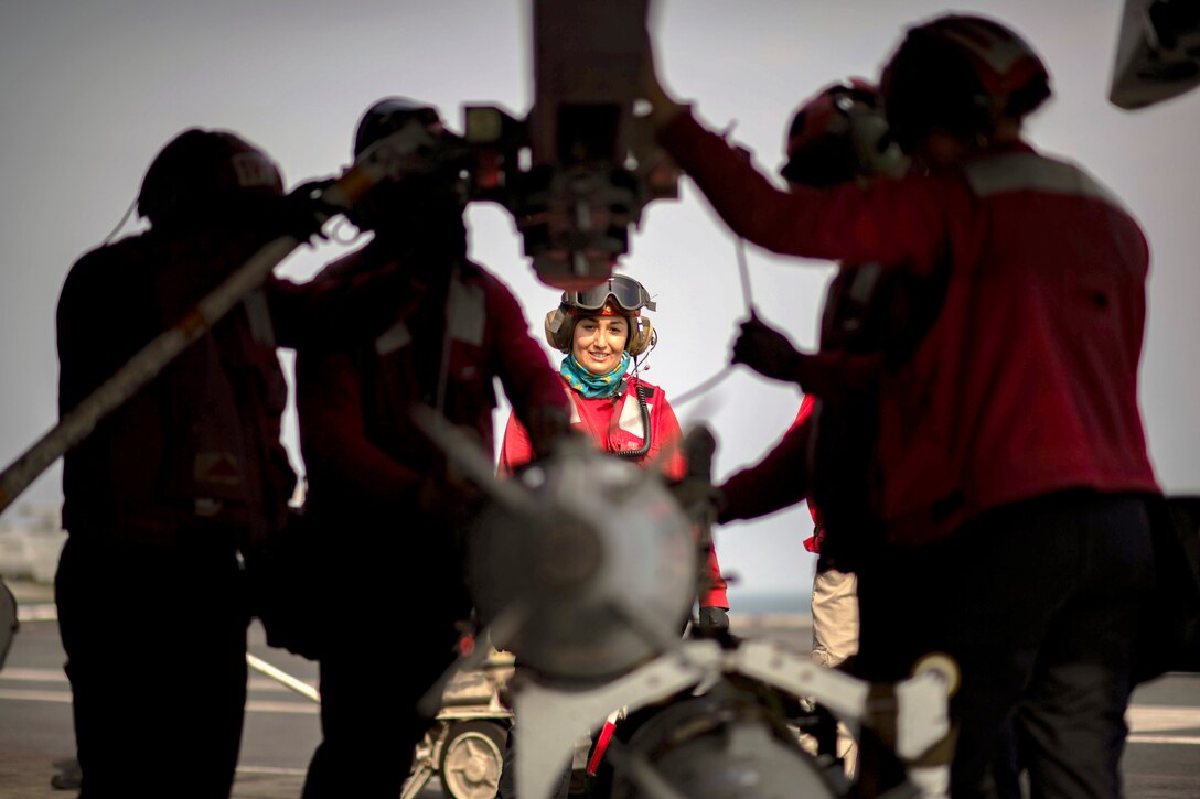 Sailors hoist a weapon into position.