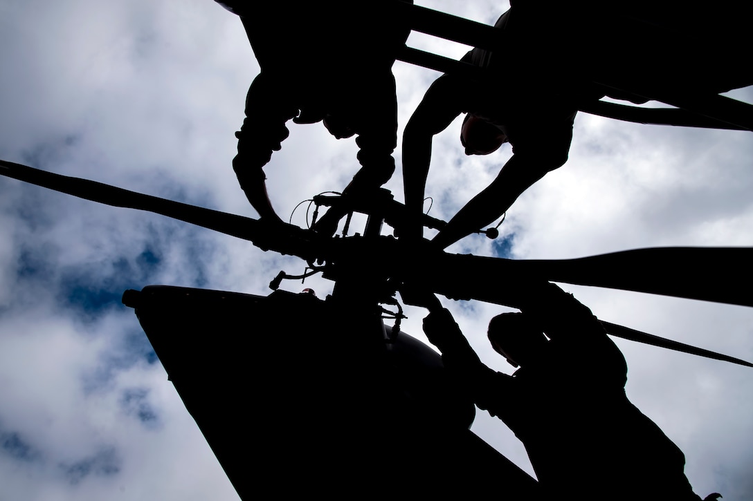 Airmen perform maintenance on the rotor of an HH-60G Pavehawk