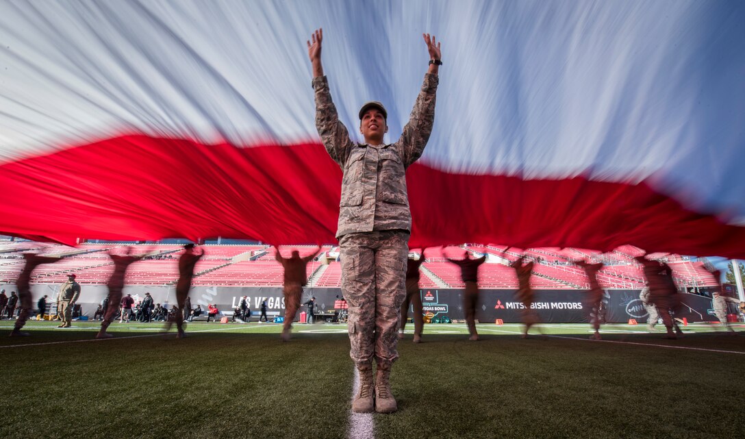 An Airman helps keep the American flag off the ground during the 2018 Las Vegas Bowl