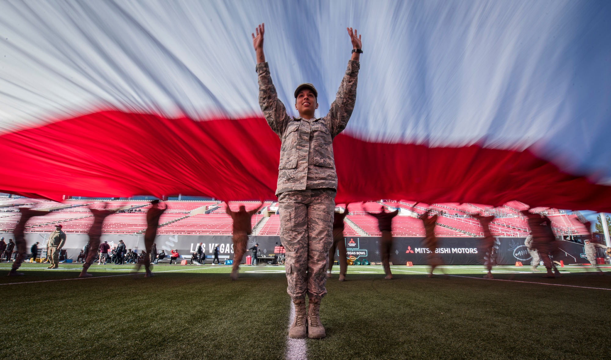 An Airman helps keep the American flag off the ground during the 2018 Las Vegas Bowl