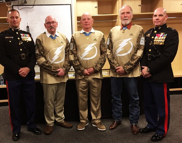 U.S. Marine Corps Colonels Devin Young, left, Marine Corps Forces, Central Command's Staff Judge Advocate and Thomas Pecina, right, MARCENT Chief of Staff, flank Medal of Honor recipients, U.S. Army Sgt. Gary Beikirch, U.S. Army Command Sgt. Maj. Gary Littrell, and U.S. Army Staff Sgt. Drew Dix for a photo during a Tampa Bay Lightning game commemorating the announcement of the 2019 Congressional Medal of Honor Society Convention. The convention will be held in Tampa 22-29 October 2019 and bring together roughly 50 of the 74 surviving Medal of Honor recipients for a week of events in the Tampa Bay area.