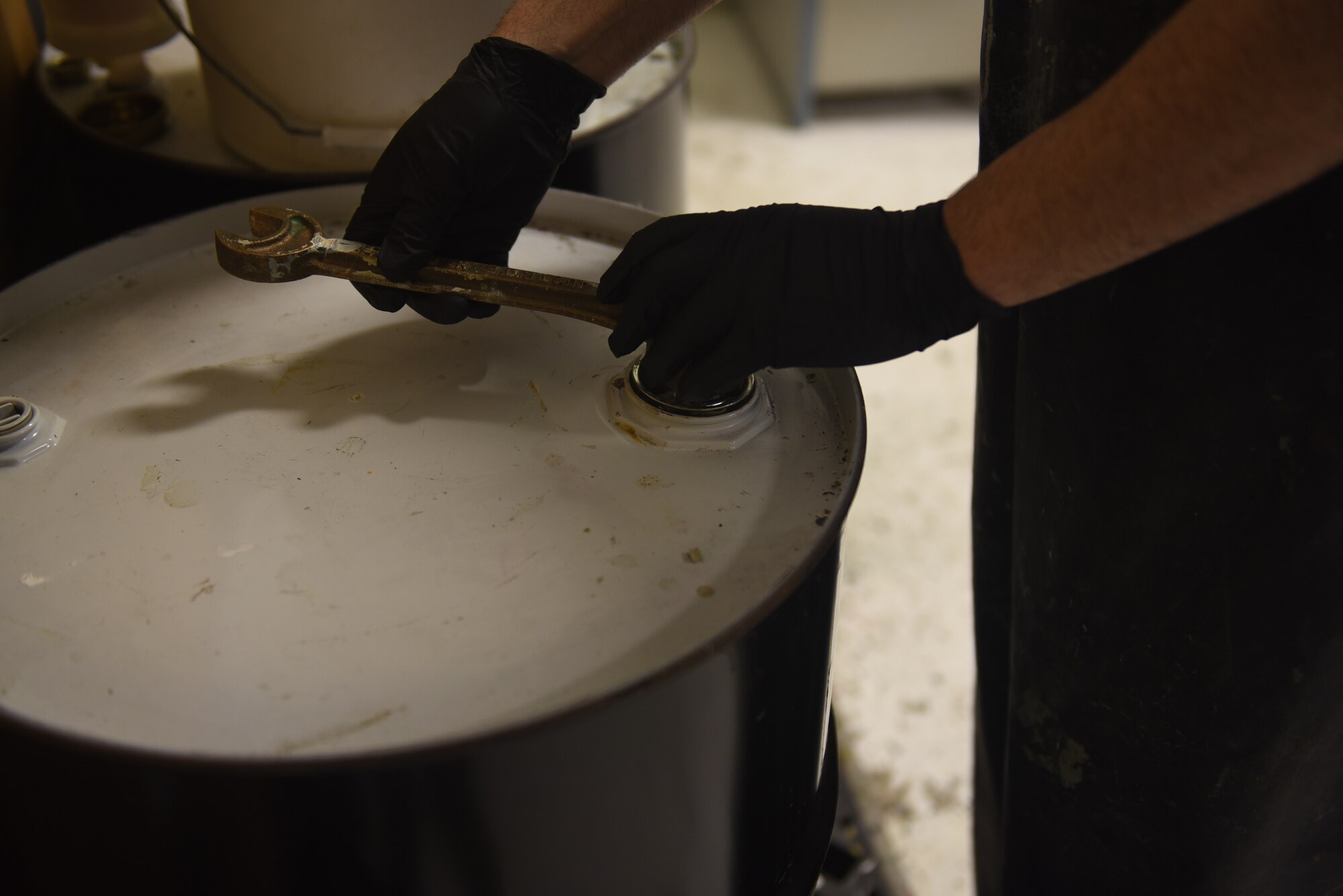 Keith Leblond, the 28th Logistic Readiness Squadron Hazmart warehouse technician, opens a drum to dispose of expired paint at Ellsworth Air Force Base, S.D., Dec. 4, 2018. Latex Paint is considered a hazardous material, which is any item that is a health or physical hazard to people, plants, or animals. (U.S. Air Force photo by Senior Airman Michella Stowers)