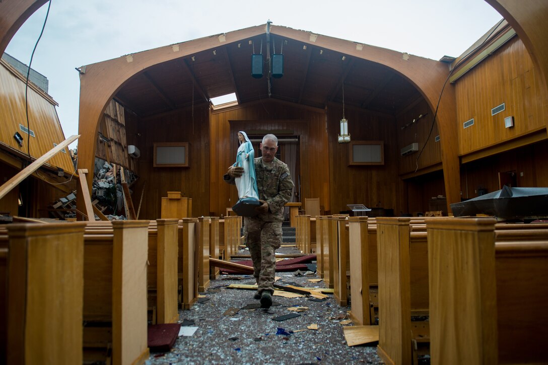 Deputy wing chaplain for Joint Base Langley, Virginia, helps carry religious items from church, October 22, 2018, on Tyndall Air Force Base, Florida, after Hurricane Michael caused catastrophic damage (U.S. Air Force/Sean Carnes)